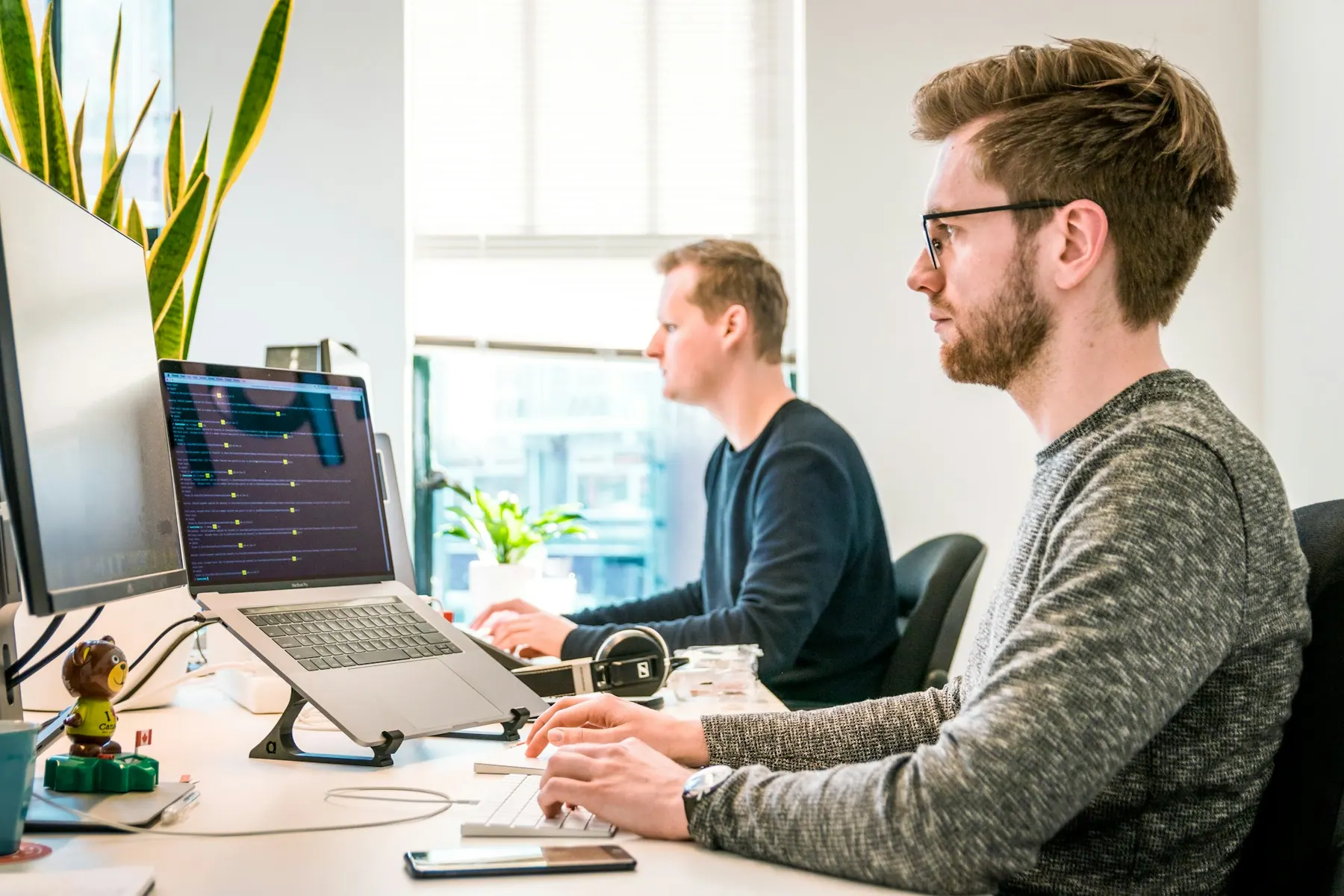 Two developers working side by side in a bright office